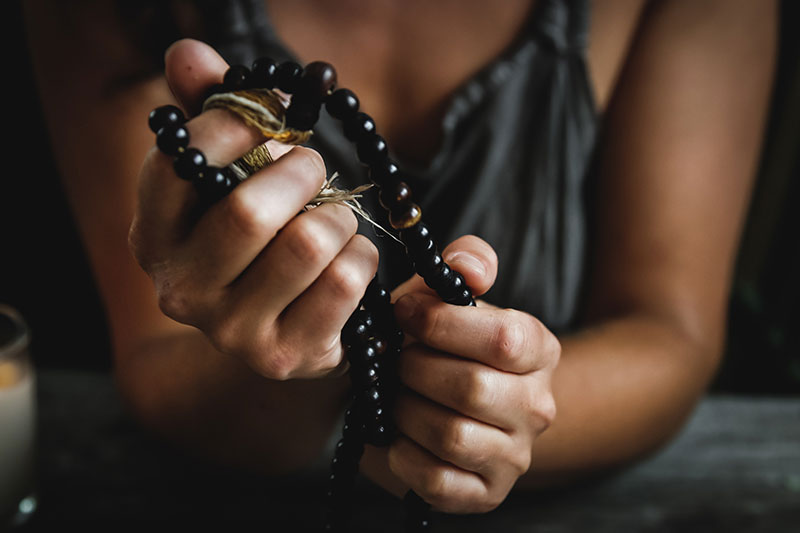 Mujer sosteniendo un amuleto fuertemente con las manos.